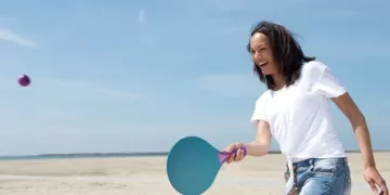 Señora jugando a palas en la playa